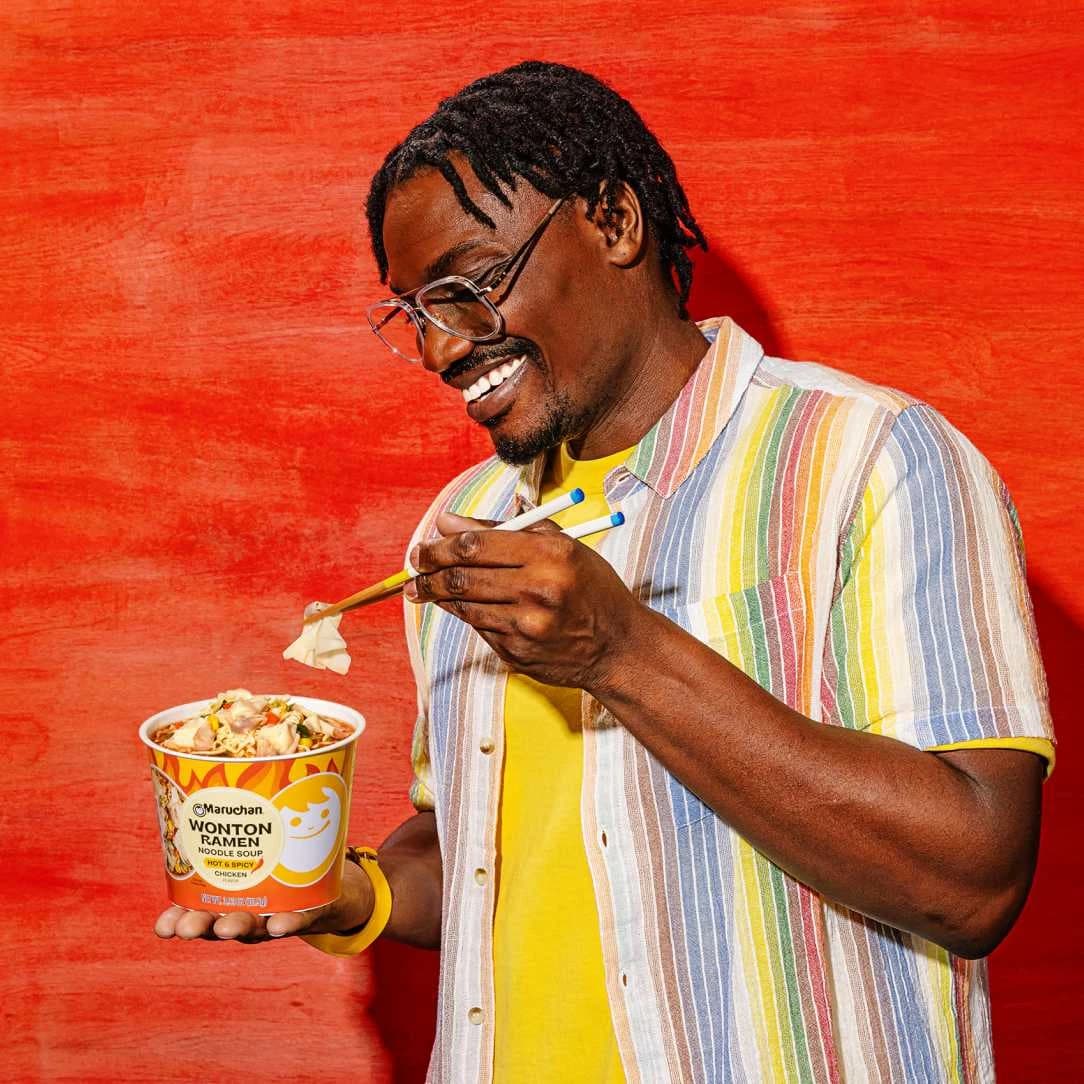 Man smiling while eating ramen with chopsticks