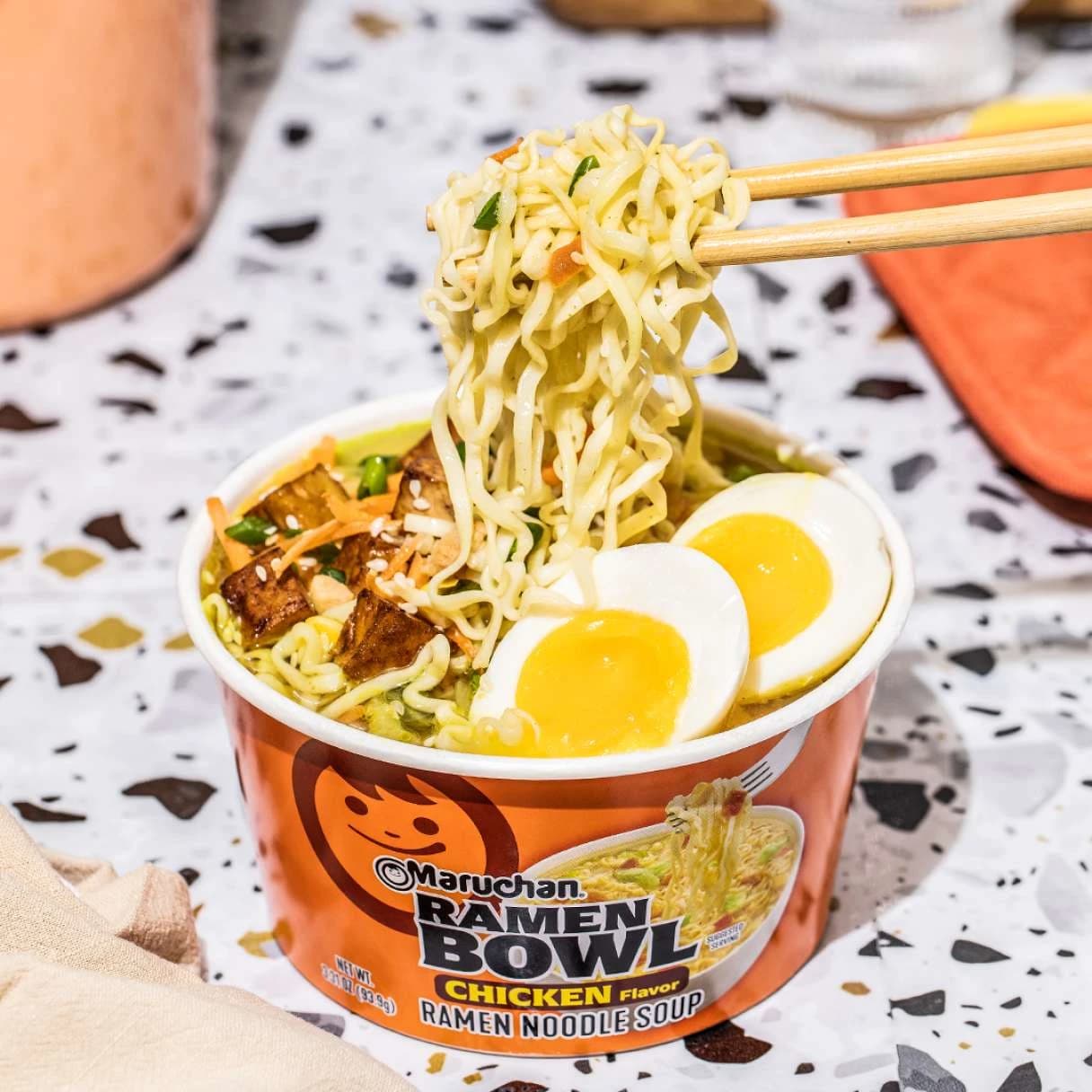 Chicken ramen bowl with chopsticks picking up noodles