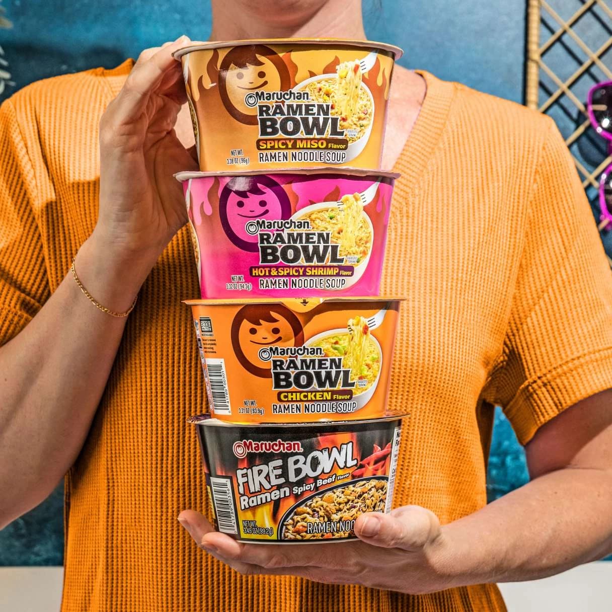 Person holding 4 Maruchan ramen bowls stacked on top of eachother