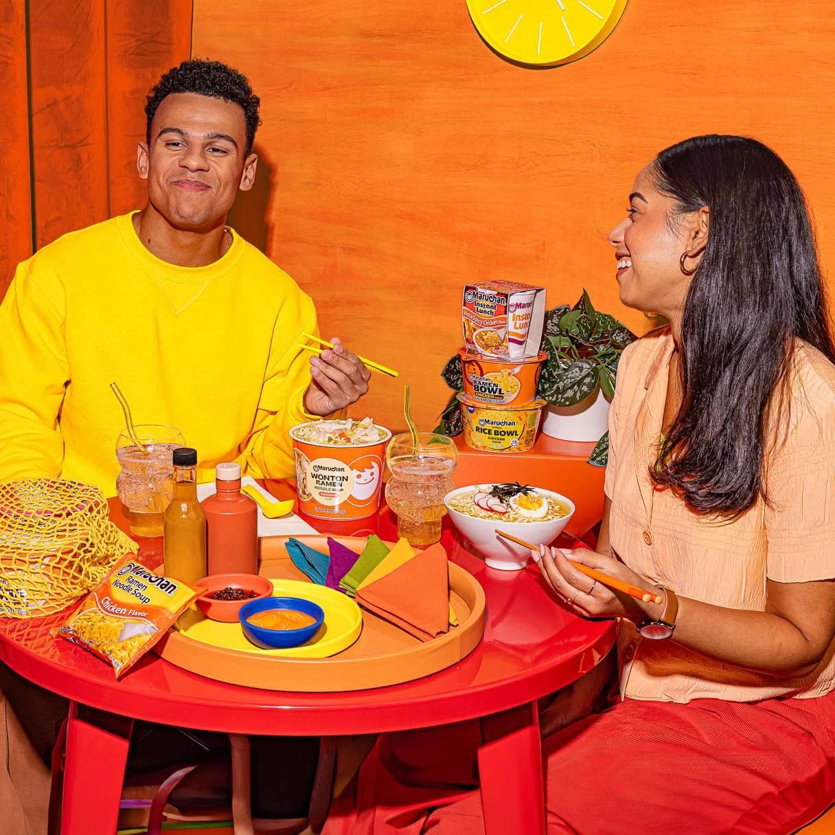People smiling while sitting at a table eating ramen together