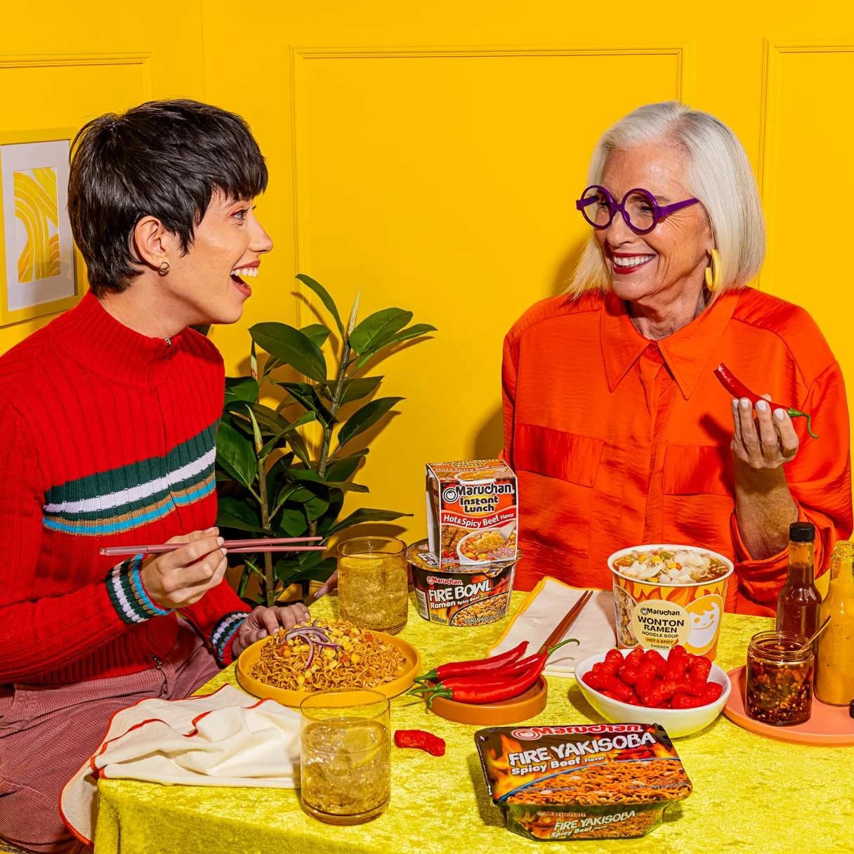 People smiling while sitting at a table eating ramen together