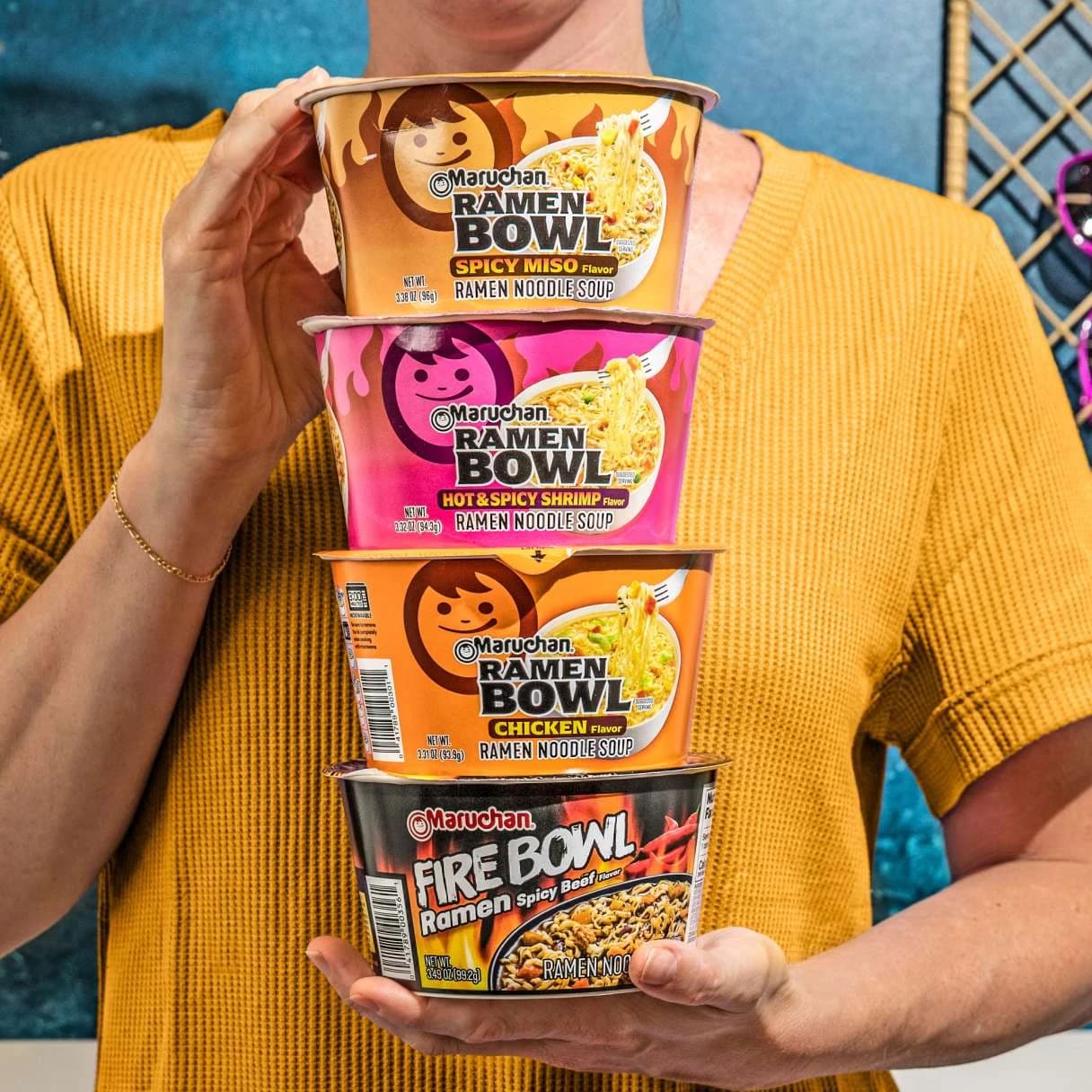 Person holding 4 Maruchan ramen bowls stacked on top of eachother