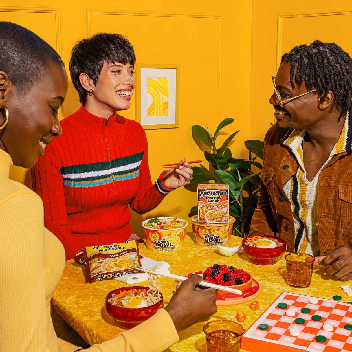 People smiling while sitting at a table eating ramen together