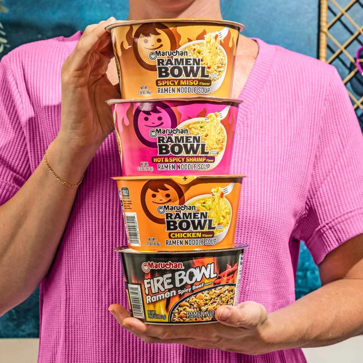 Person holding 4 Maruchan ramen bowls stacked on top of eachother