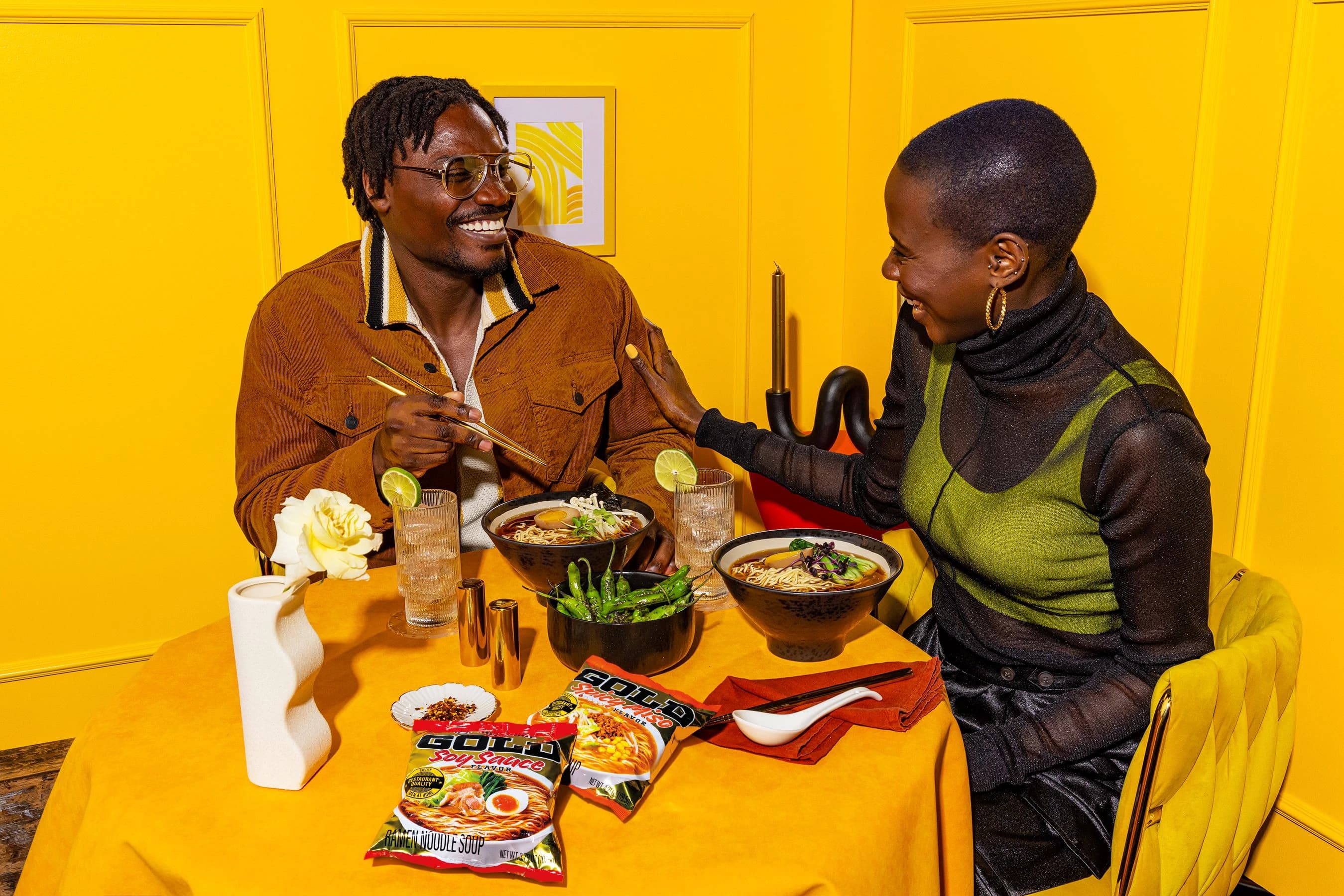 Two people sitting at a dining table eating ramen.