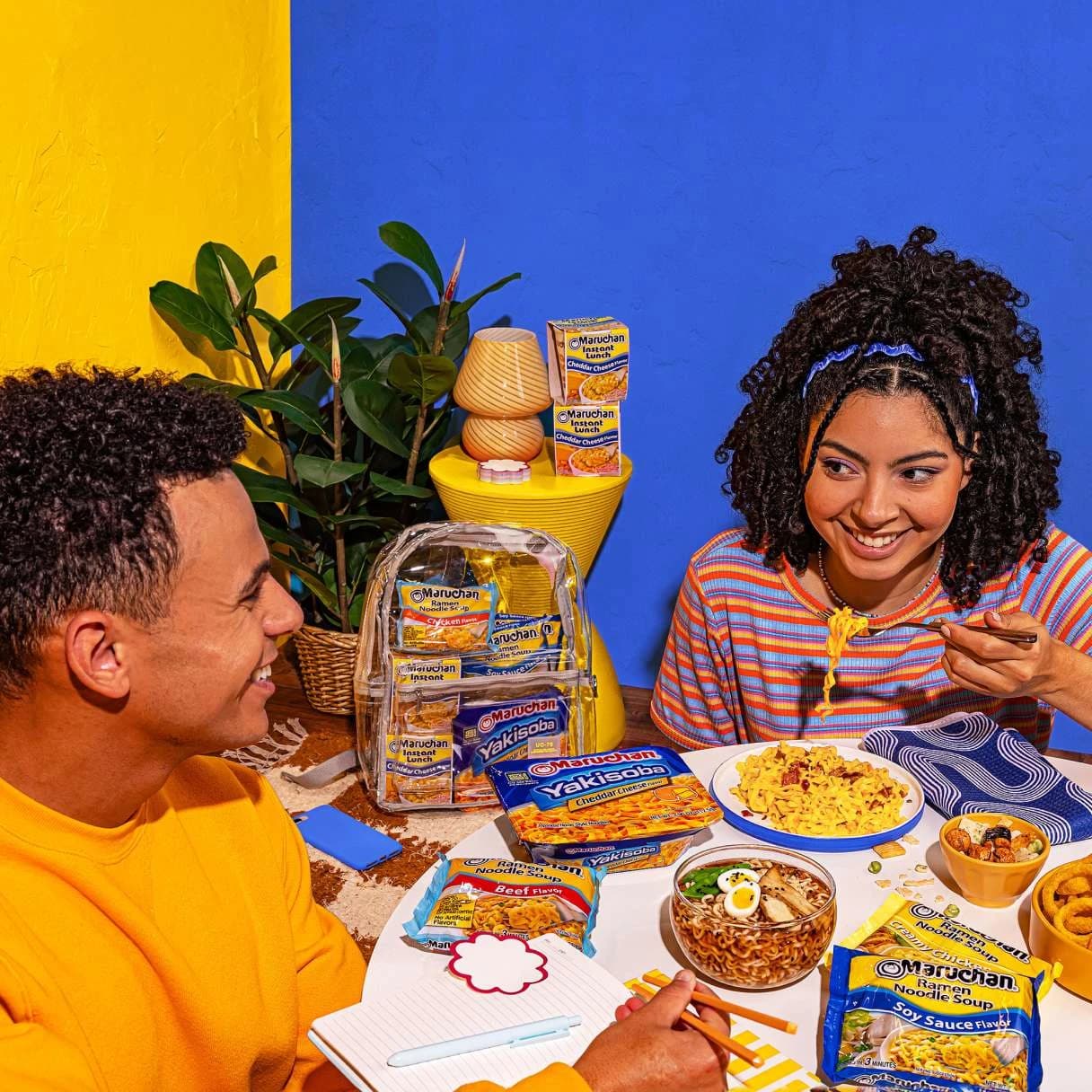 People smiling and eating ramen at a dining table