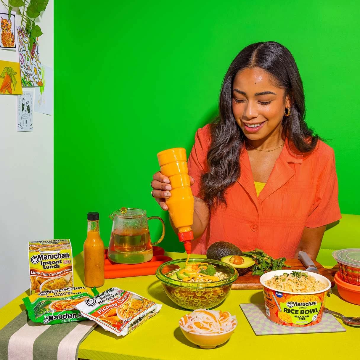 Woman squeezing sauce on top of her bowl of ramen at a dining table