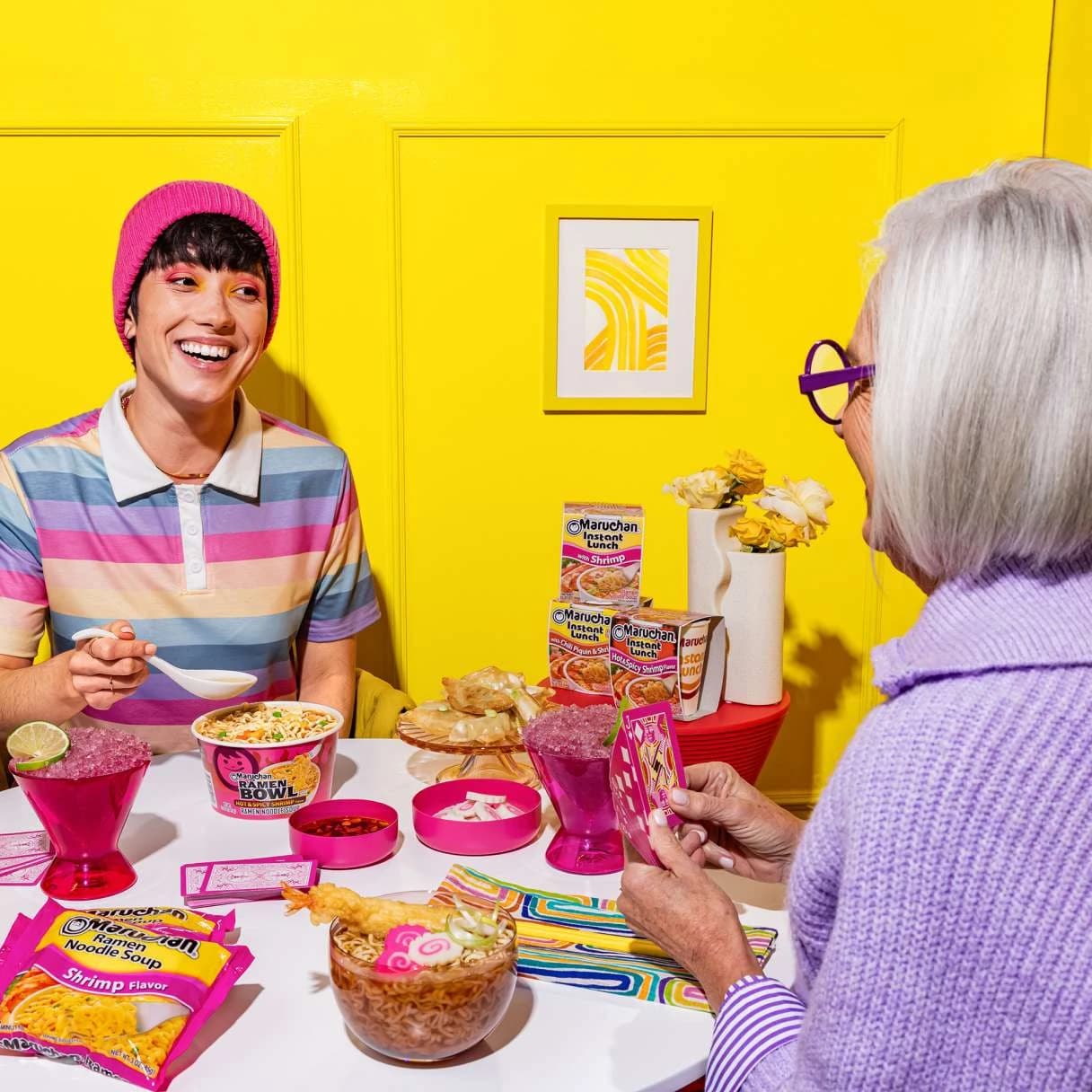 People sitting at a dining table smiling while eating ramen