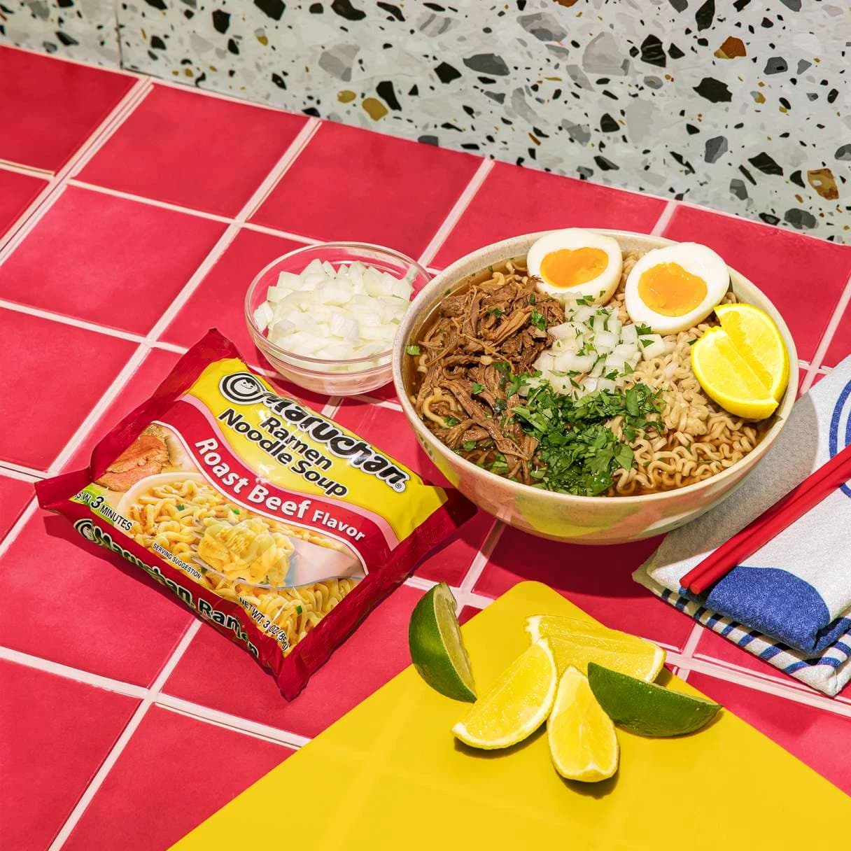 Ramen in a bowl next to a package of roast beef flavor ramen