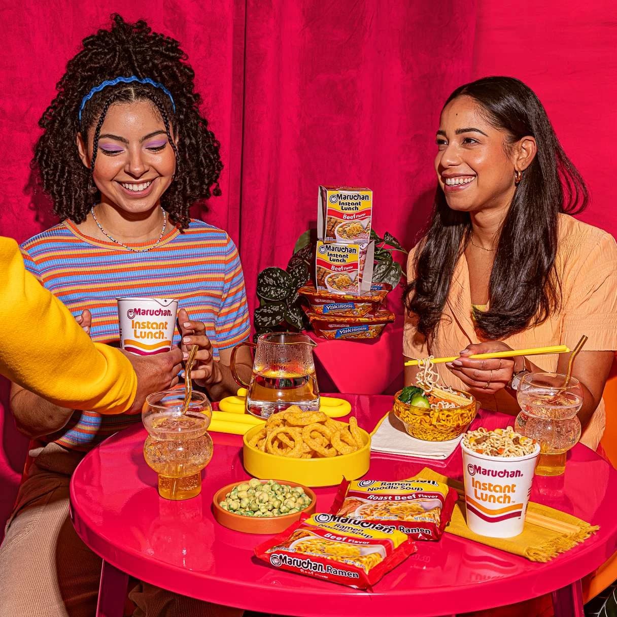 Women smiling while eating Maruchan ramen at a dining table