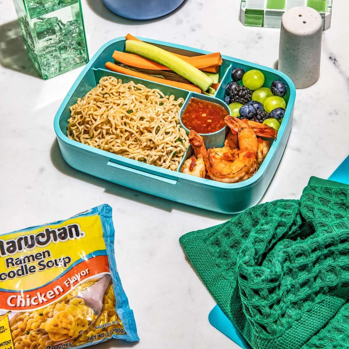 A bento box of ramen with vegetables on a table
