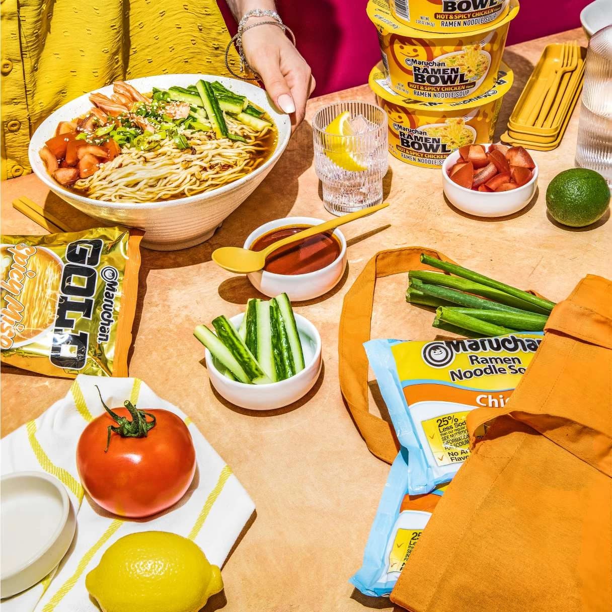 A bowl of ramen on a table with vegetables around