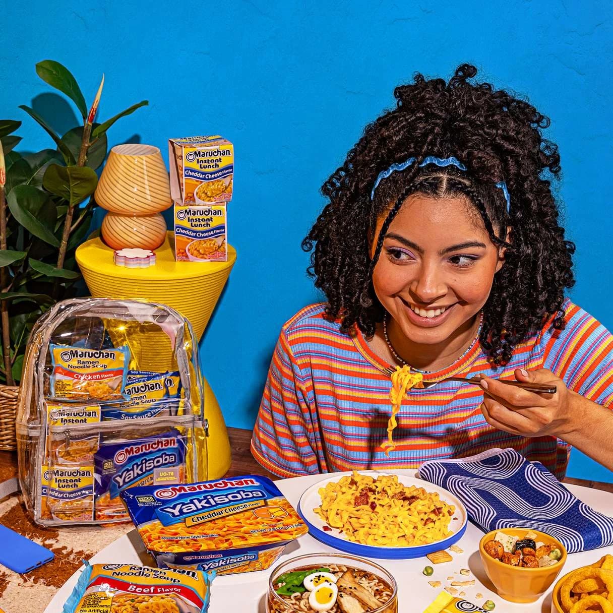 Woman smiling while eating a bowl of ramen at a table