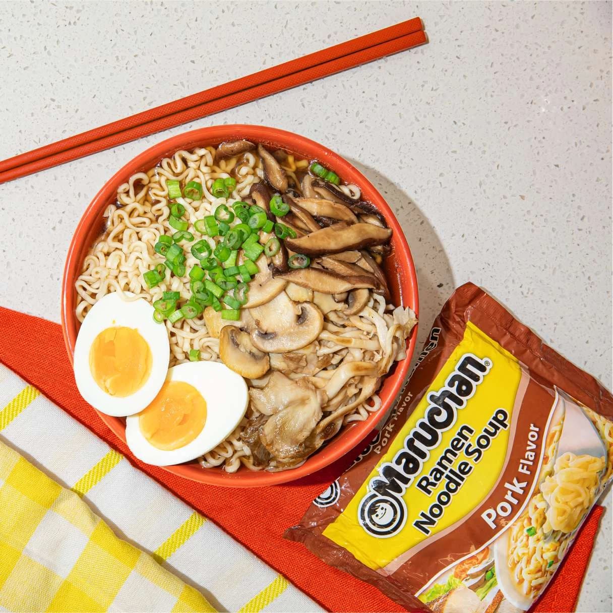 A bowl of pork flavor ramen next to a package of Maruchan pork flavor ramen