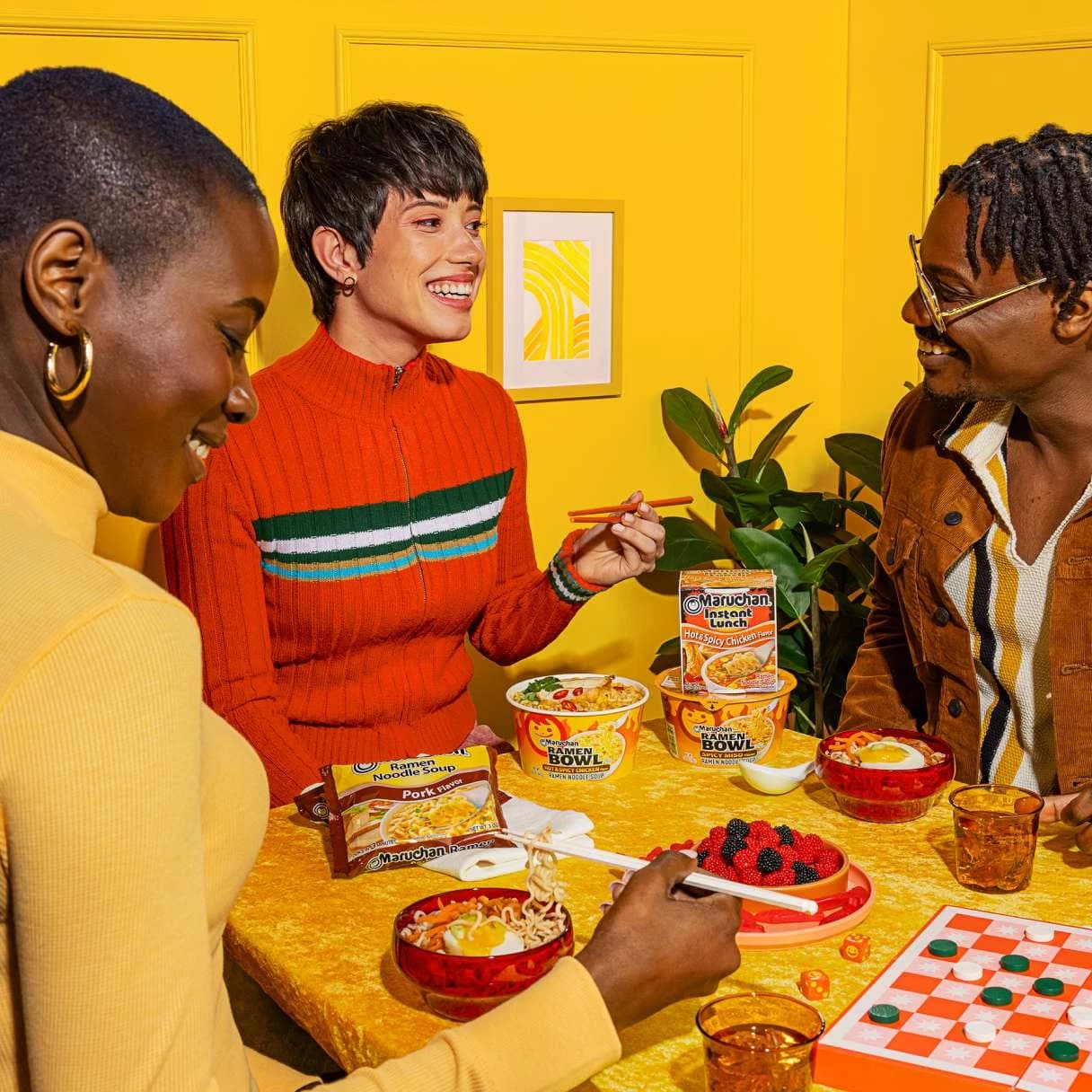 People smiling at a dinner table while eating ramen