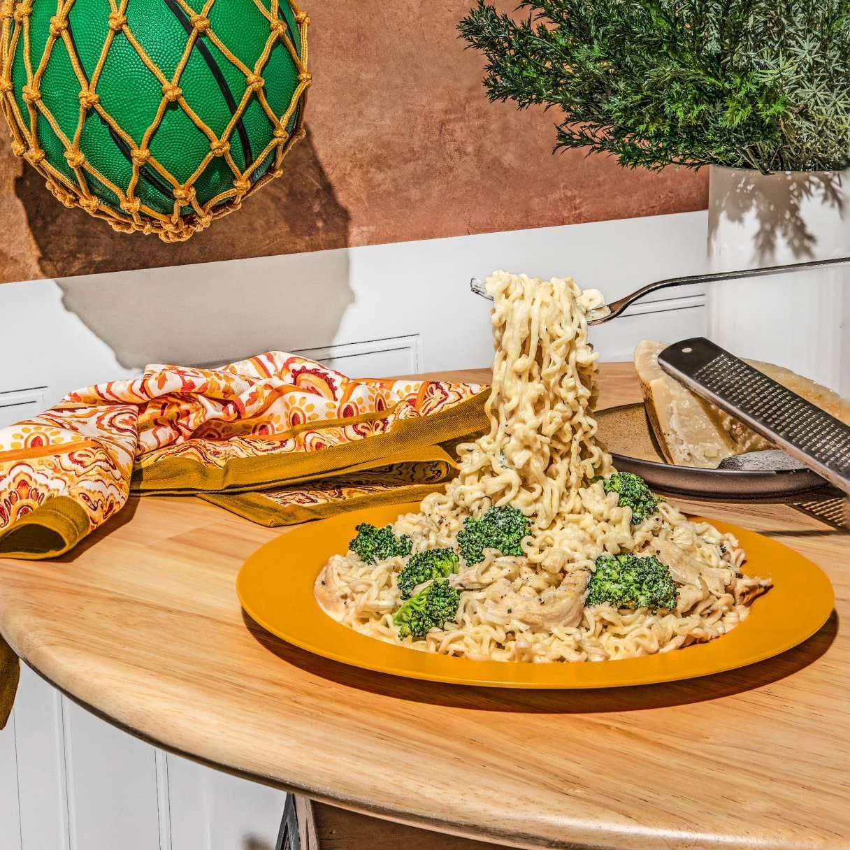 Ramen on a plate on a table with noodles being picked up by a fork